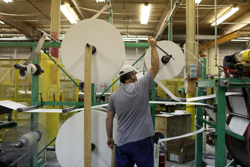 An employee operates a paper machine at the American Disposables Inc. factory, 2009 in Ware, Massachusetts. Photo credit: Spencer Platt / Staff